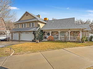 View of front of home with a garage, a front yard, and covered porch