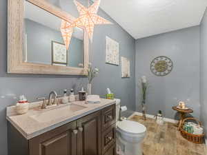 Bathroom featuring vanity, hardwood / wood-style floors, a textured ceiling, and toilet