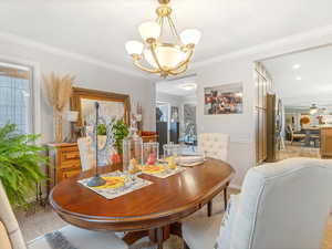 Dining area featuring ornamental molding and ceiling fan with notable chandelier