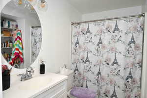 Bathroom featuring vanity, curtained shower, and toilet