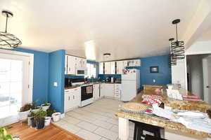 Kitchen featuring white cabinetry, white appliances, and hanging light fixtures