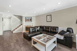 Living room with a premium fireplace, wood-type flooring, and ornamental molding