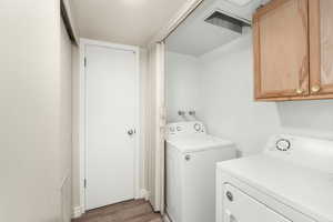 Laundry area featuring cabinets, wood-type flooring, and separate washer and dryer