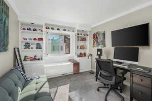 Home office with ornamental molding and light carpet