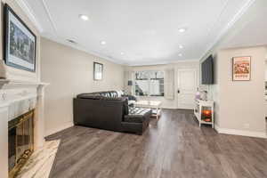 Living room with crown molding, a premium fireplace, and dark hardwood / wood-style flooring