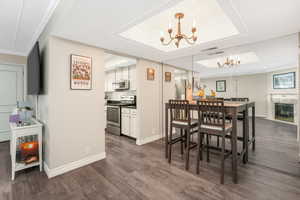 Dining space with a raised ceiling, dark hardwood / wood-style flooring, and an inviting chandelier