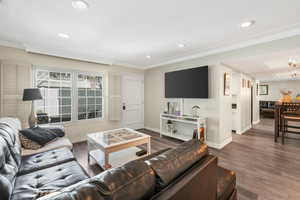 Living room with crown molding, wood-type flooring, and an inviting chandelier