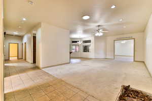 Unfurnished living room featuring ceiling fan and light carpet