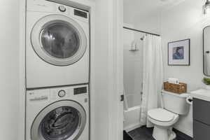 Laundry room with stacked washer / drying machine and a textured ceiling