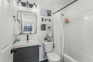 Full bathroom with new vanity, new shower / new bathtub combination with curtain, and toilet and new stone floor.