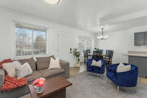 Living room featuring crown molding, light tile patterned floors, a textured ceiling, and a chandelier