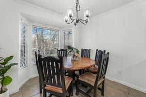 Dining space with crown molding, a notable chandelier, and tile patterned floors