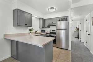 Kitchen featuring sink, gray cabinets, appliances with stainless steel finishes, backsplash, and kitchen peninsula