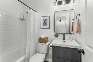 Full bathroom featuring new shower / new bathtub combination with curtain, new vanity, and toilet, new stone floor.