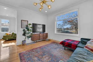 Living room featuring crown molding, a notable chandelier, and hardwood / wood-style flooring