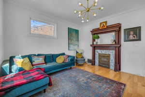 Living room featuring ornamental molding, hardwood / wood-style floors, a notable chandelier, and a fireplace