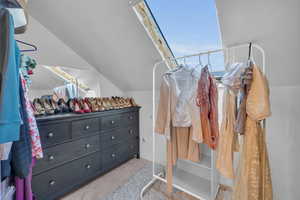 Walk in closet with light colored carpet and lofted ceiling