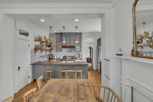 Kitchen featuring ornamental molding, decorative light fixtures, kitchen peninsula, and a breakfast bar area