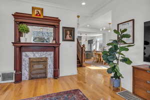 Interior space featuring hardwood / wood-style flooring, a premium fireplace, crown molding, and a chandelier