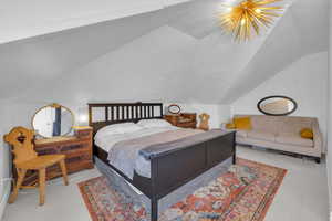 Bedroom with lofted ceiling and a notable chandelier