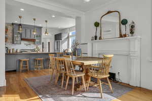 Dining space featuring ornamental molding, sink, and light wood-type flooring