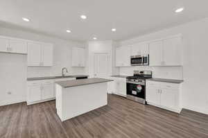 Kitchen featuring sink, a center island, white cabinets, and appliances with stainless steel finishes