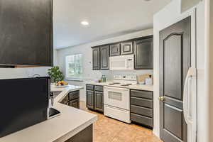 Kitchen with light tile patterned flooring and white appliances