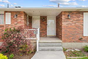 Property entrance featuring covered porch and brick siding