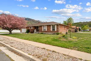 Ranch-style home with brick siding, a front lawn, a mountain view, and concrete driveway