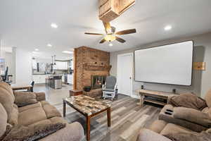 Home theater room featuring ceiling fan, a fireplace, and light hardwood / wood-style flooring