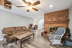 Living room featuring a brick fireplace, hardwood / wood-style floors, and ceiling fan