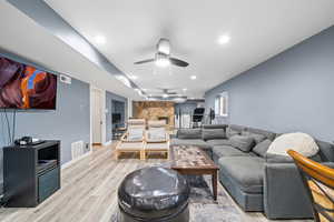 Living room with ceiling fan and light hardwood / wood-style flooring