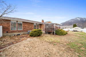 Rear view of property featuring a mountain view, a yard, and cooling unit