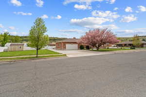 Obstructed view of property with a residential view, brick siding, a garage, a front yard, and concrete driveway