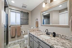 Bathroom with vanity, toilet, an enclosed shower, and hardwood / wood-style floors