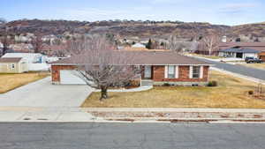 Single story home featuring a garage, a mountain view, and a front lawn