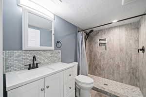 Bathroom featuring vanity, walk in shower, a textured ceiling, and toilet