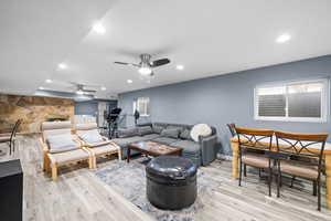 Living room featuring light hardwood / wood-style flooring, a fireplace, and ceiling fan