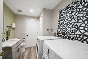 Washroom with light wood-type flooring, sink, and independent washer and dryer