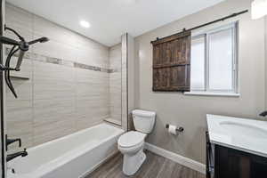 Full bathroom with vanity, hardwood / wood-style flooring, toilet, and tiled shower / bath combo