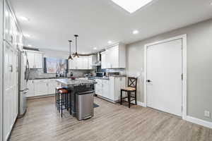 Kitchen with white cabinetry, a kitchen island, a breakfast bar, and appliances with stainless steel finishes