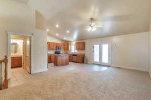 Kitchen with light carpet, a kitchen island, ceiling fan, and appliances with stainless steel finishes