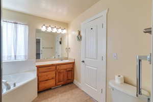 Bathroom with vanity, a tub, tile patterned floors, and toilet