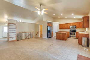 Kitchen with appliances with stainless steel finishes, sink, a center island, ceiling fan, and light carpet