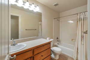 Full bathroom with toilet, tile patterned floors, vanity, and shower / bathtub combination with curtain