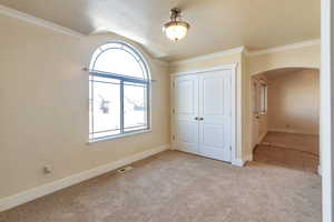 Unfurnished bedroom featuring crown molding, light carpet, and a closet