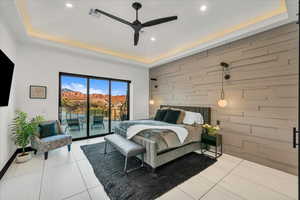 Bedroom featuring ceiling fan, tile patterned floors, a tray ceiling, and access to outside