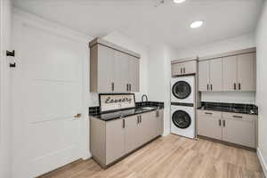 Clothes washing area with stacked washer / dryer and light hardwood / wood-style floors