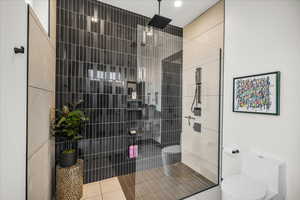 Bathroom featuring toilet, tile patterned flooring, and a tile shower