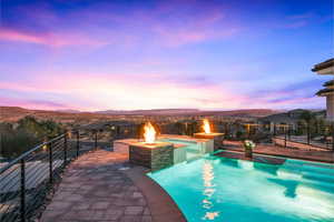 Pool at dusk with an outdoor fire pit, a mountain view, and a patio area